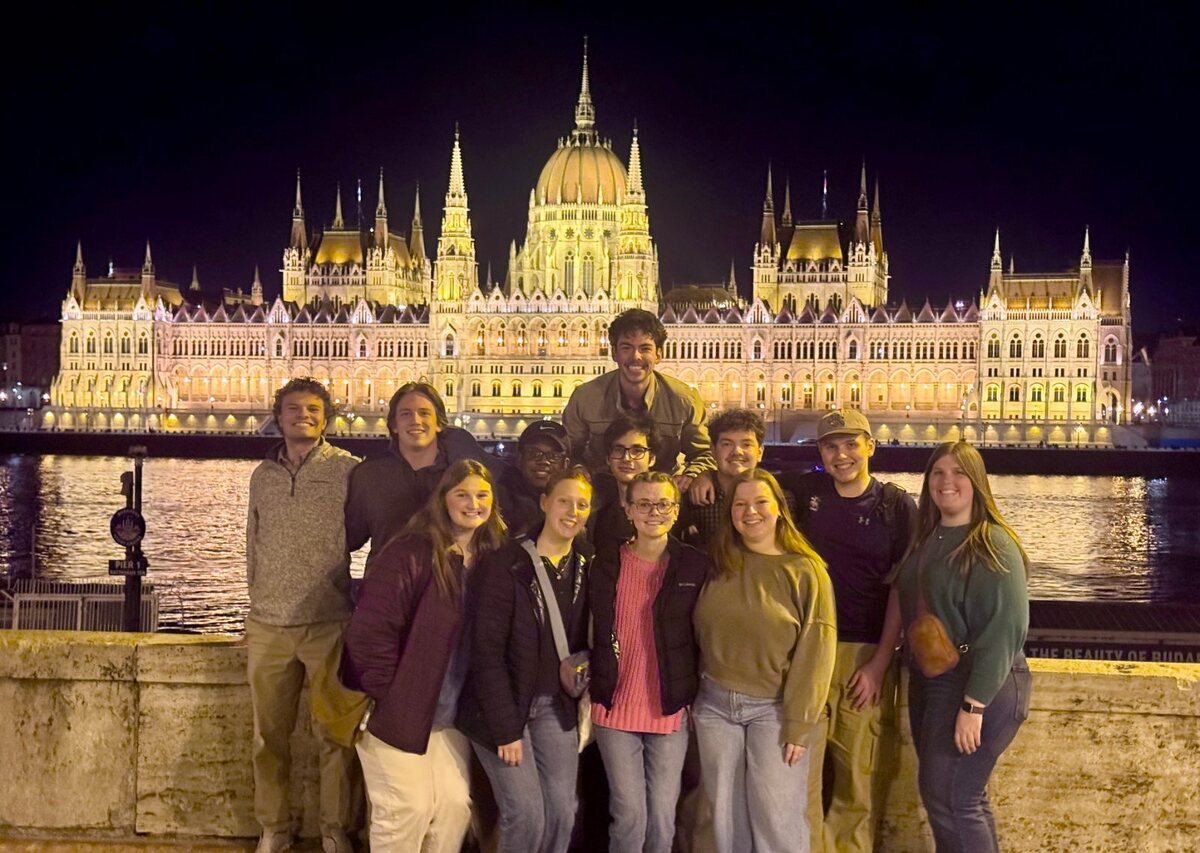 Students together in front of the Hungarian Parliament at night